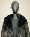 Mannequin wearing a black fake fur coat with a plain background