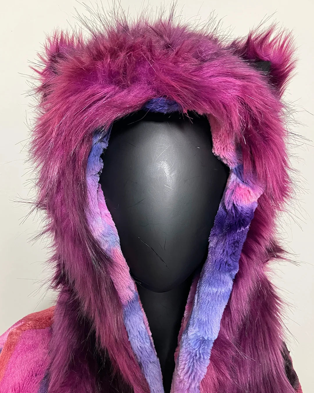 Purple and pink fur hood on a mannequin head against a plain background