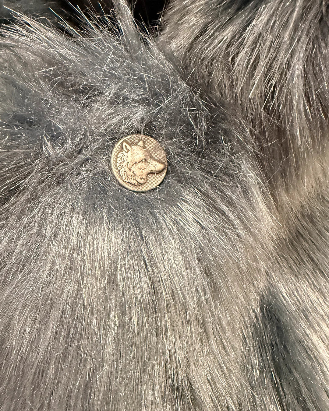 Close-up of a wolf face button on the Blue Wolf Faux Fur Luxe SpiritHoods Coat