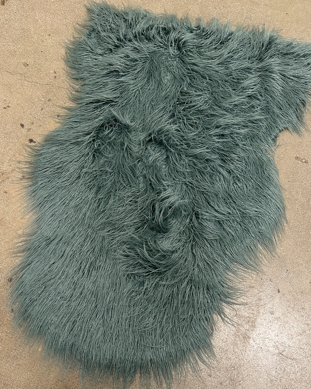Teal shaggy faux fur rug on a beige floor