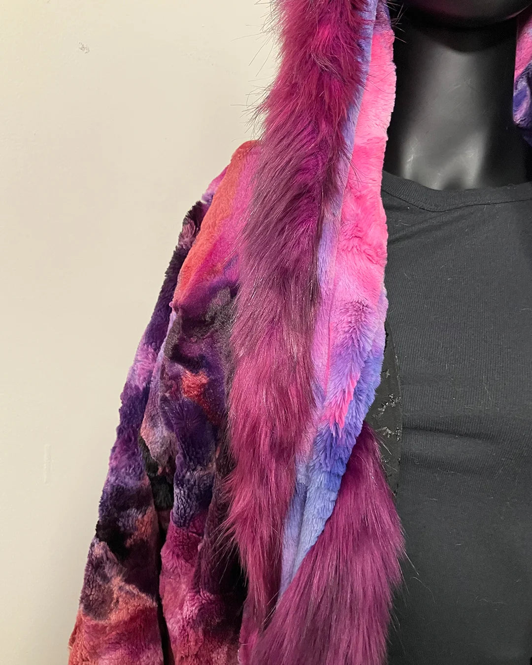 Mannequin wearing a colorful fur coat with a neutral background