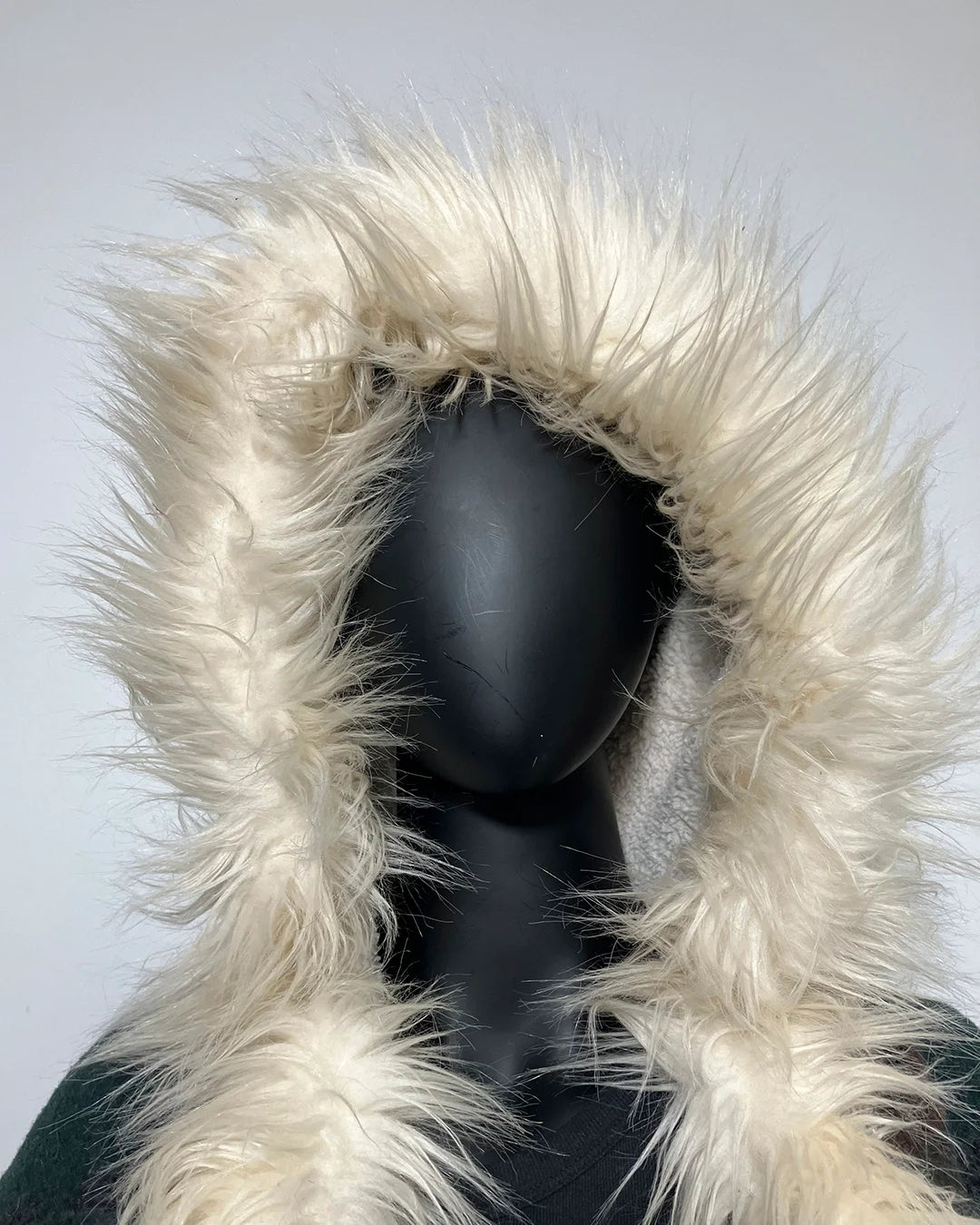 Mannequin wearing a coat with a fluffy white hood against a light gray background
