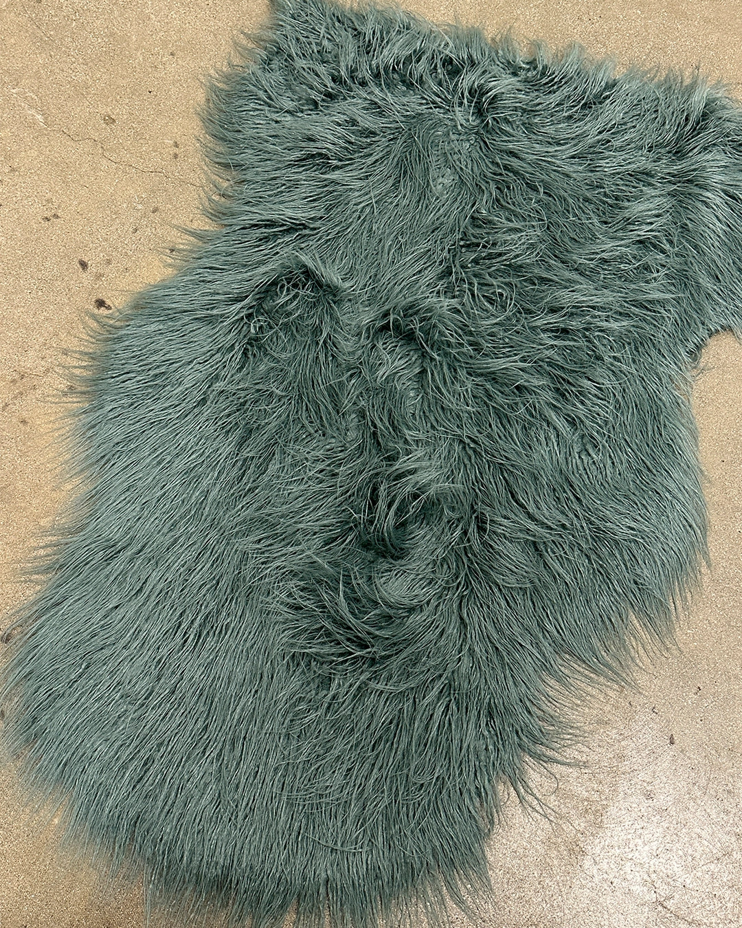 Teal shaggy faux fur rug on a beige floor
