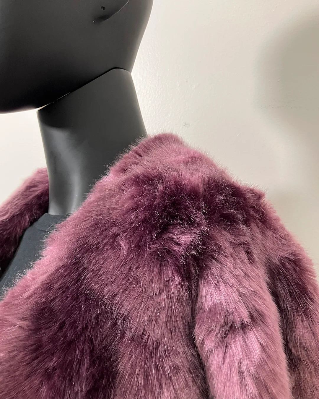 Close-up of a lavender purple fake fur coat on a mannequin against a neutral background