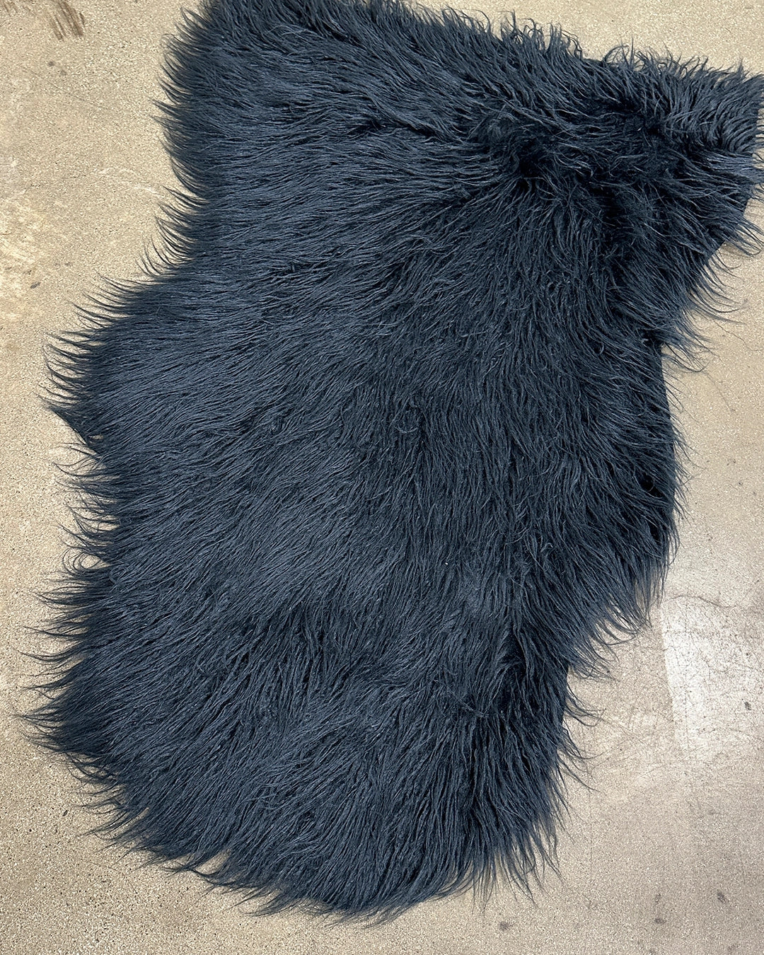 Dark blue shaggy fur rug on a concrete floor