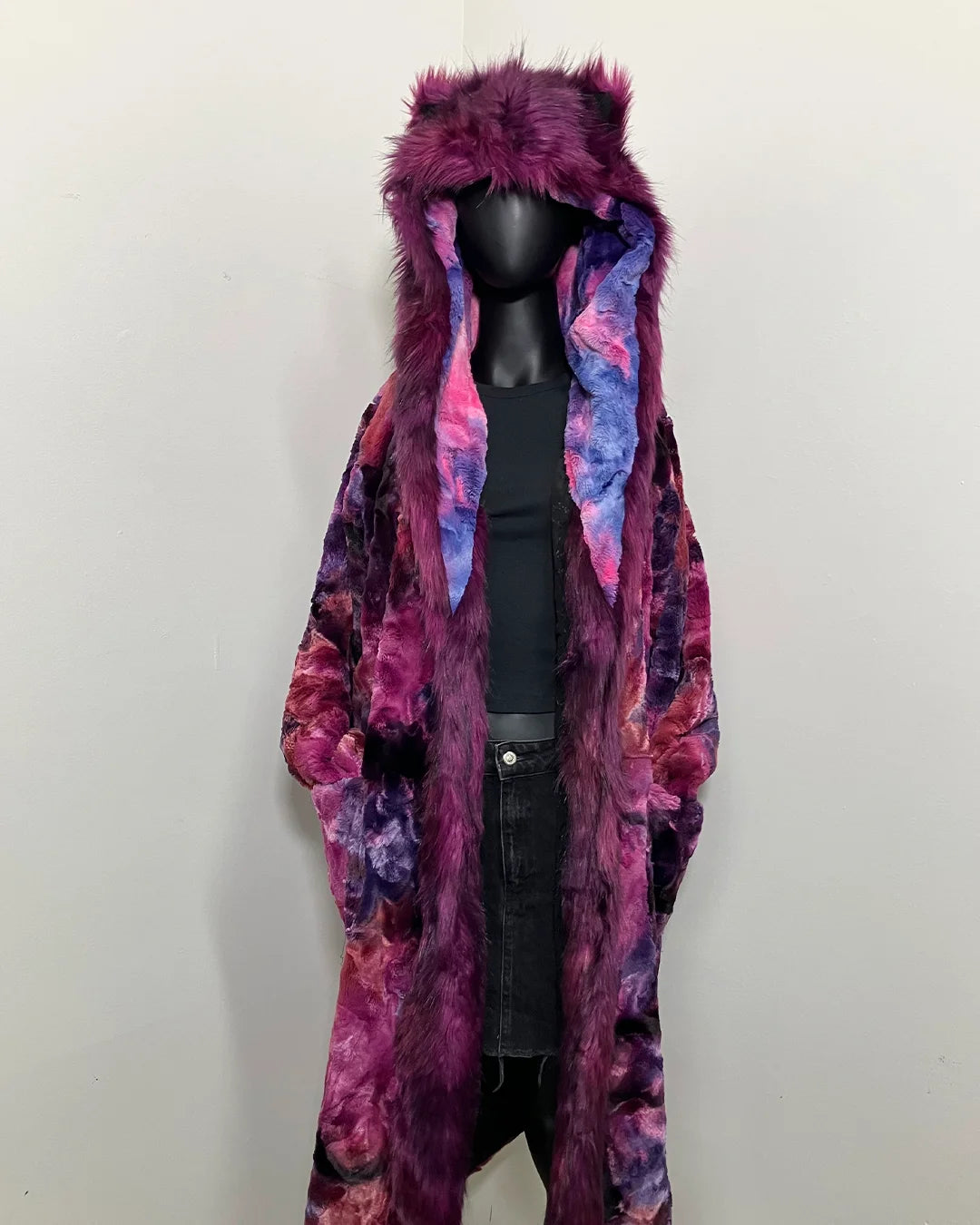Mannequin wearing a long, colorful tiedye faux fur robe-coat with a hood on a white background