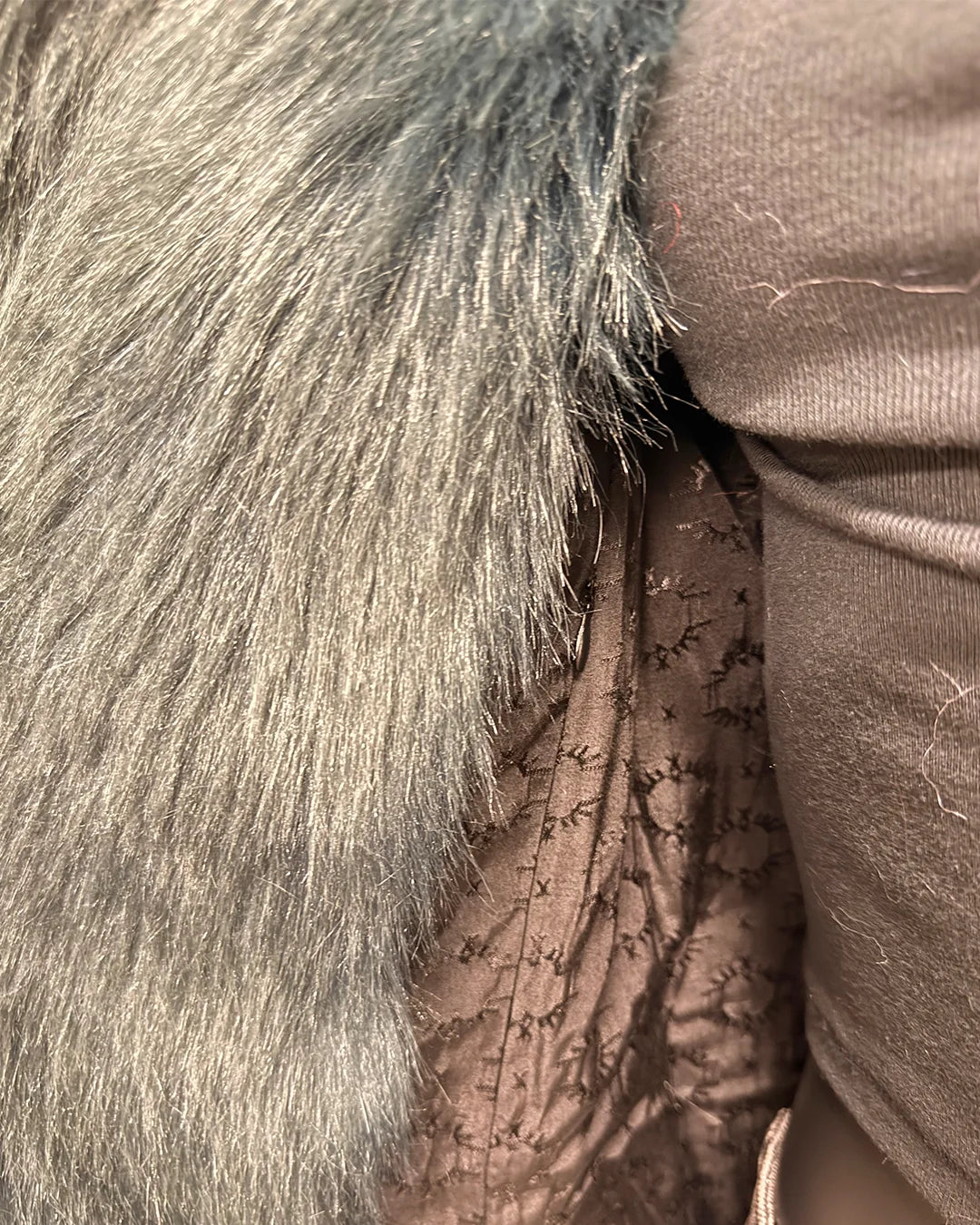 Close-up of faux fur and textured fabric with a focus on texture and color showing the inner lining with the SpiritHoods logo and inner zipper pocket