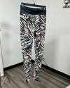 Ivory and Black Zebra striped leggings with a black waistband on a black hanger.