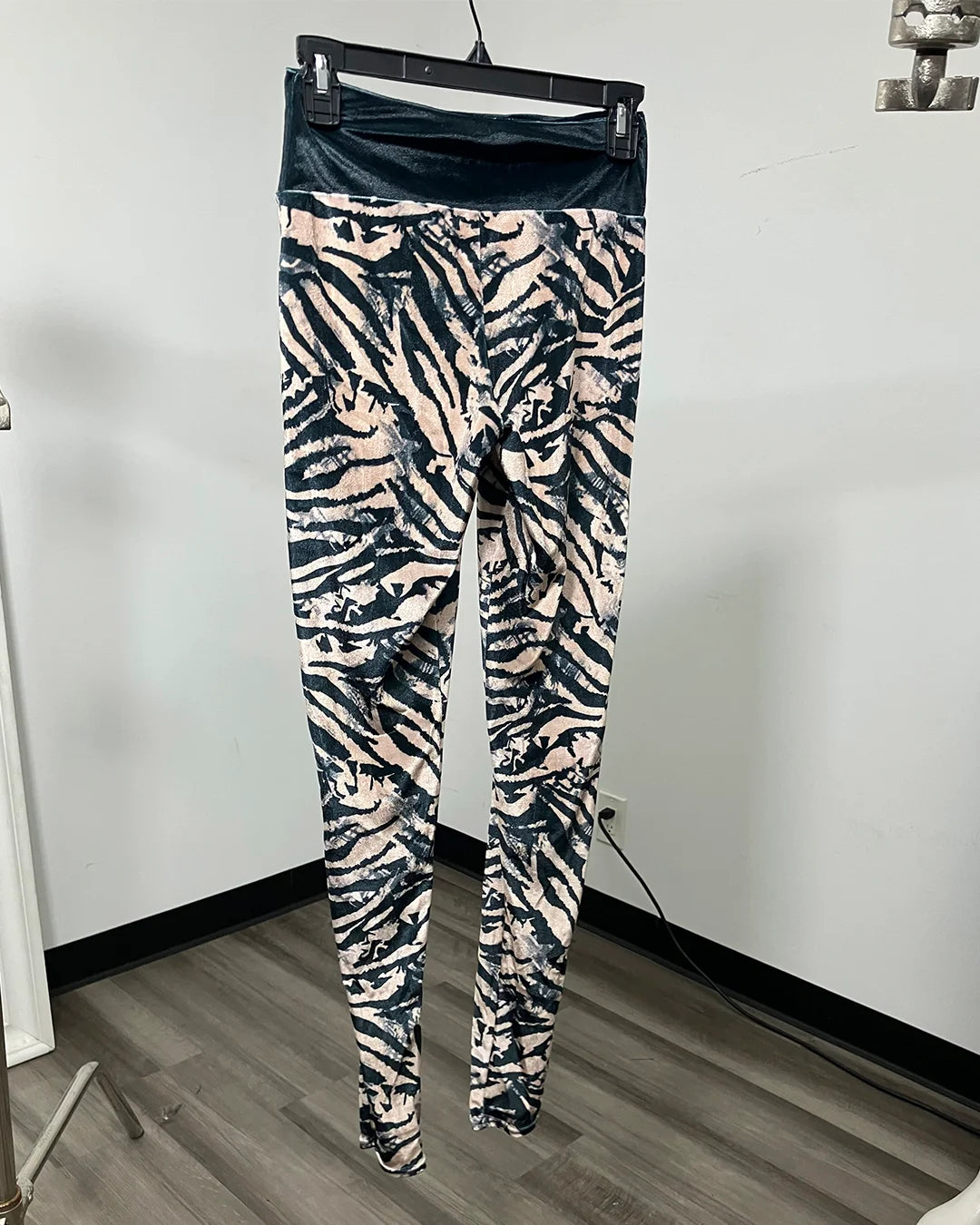 Ivory and Black Zebra striped leggings with a black waistband on a black hanger.