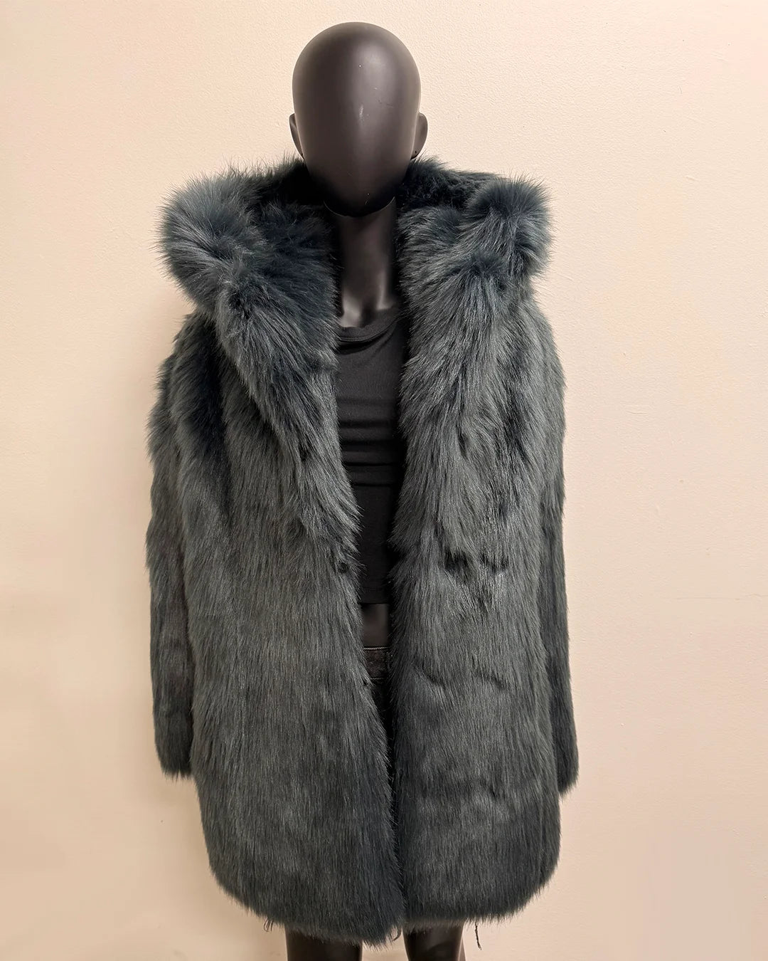 Mannequin wearing a long gray/blue fake fur coat with a hood on a beige background