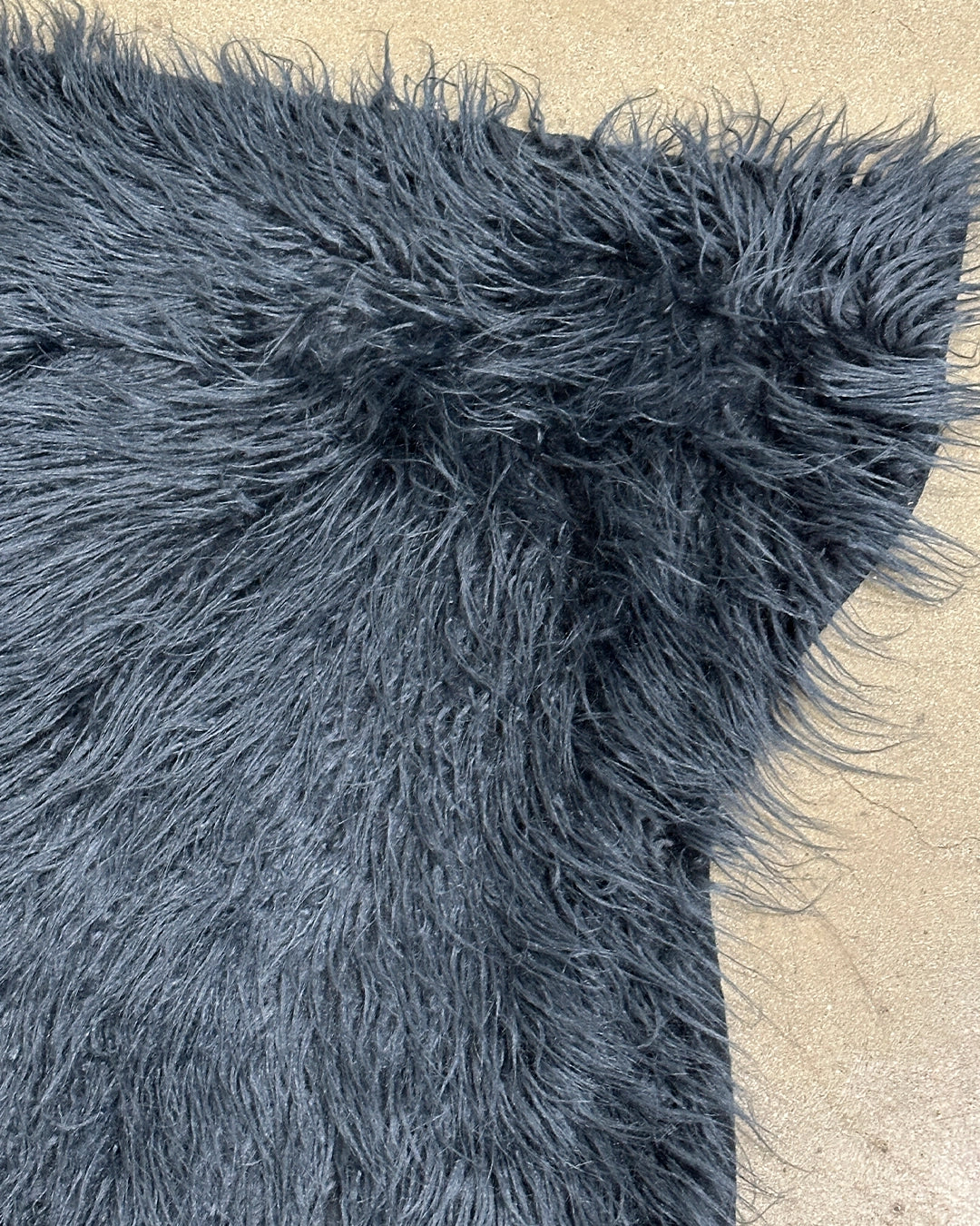 Dark blue fluffy faux fur rug on a concrete floor