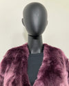 Mannequin wearing a purple fake fur coat against a plain background