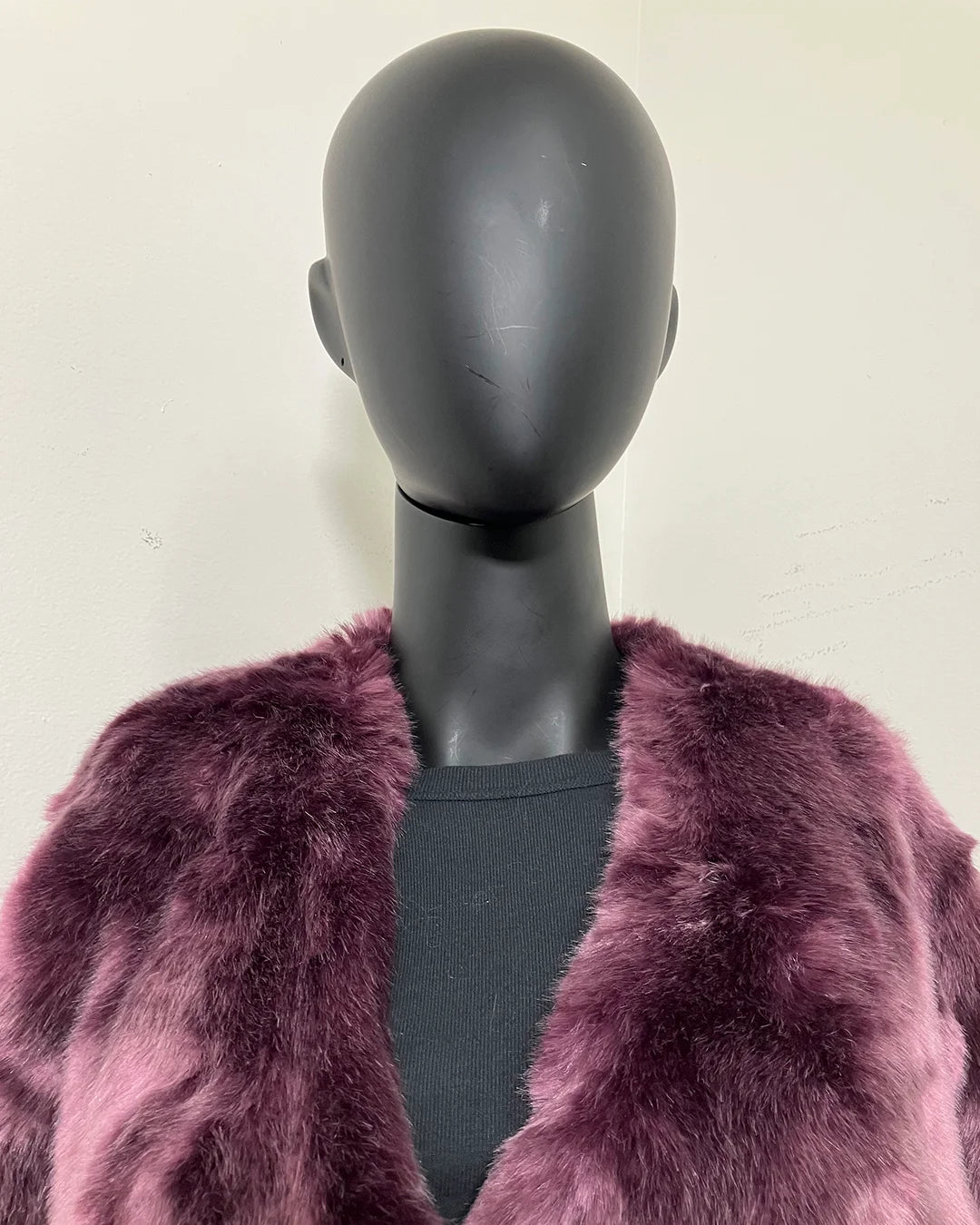Mannequin wearing a purple fake fur coat against a plain background