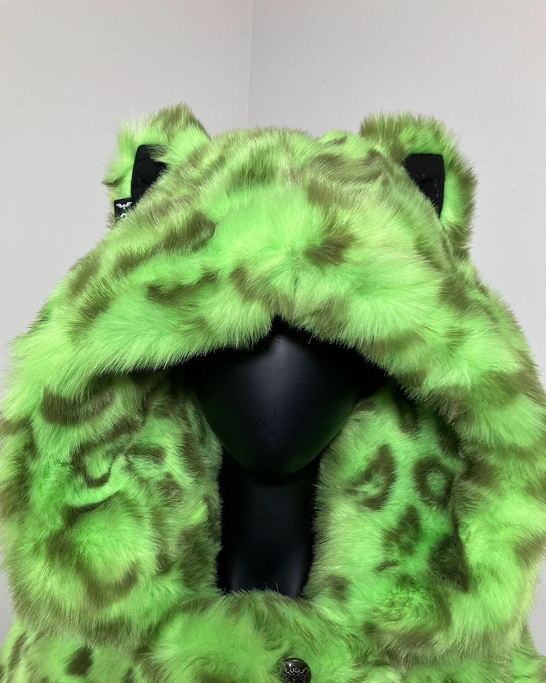 Green fake fur coat with black leopard print pattern on a white background - close up photo of the ears