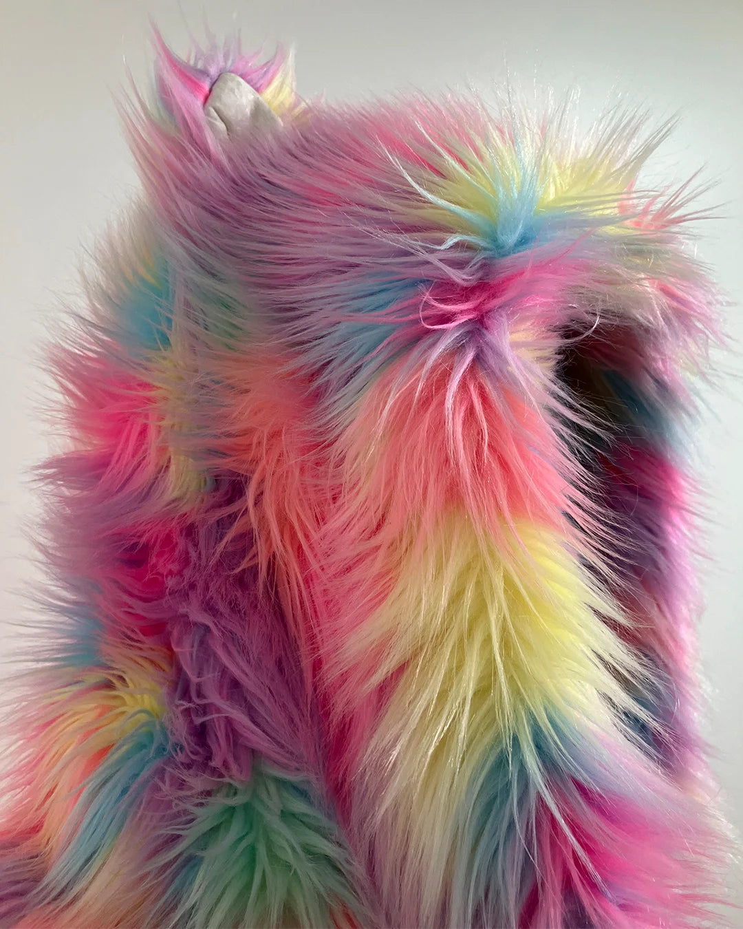Multicolored fluffy colorful fake fur hood with cat ears, featuring a pastel rainbow pattern on a white background