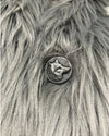 Metallic button with a wolf design on a textured fur background