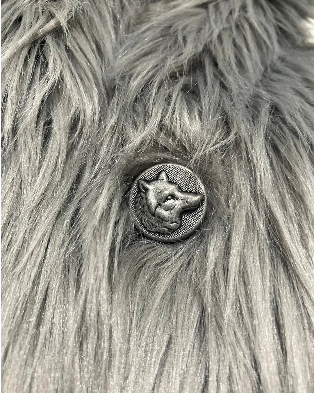 Metallic button with a wolf design on a textured fur background