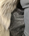 Close-up of a textured black snakeskin fabric with a grey faux fur trim on a dark background