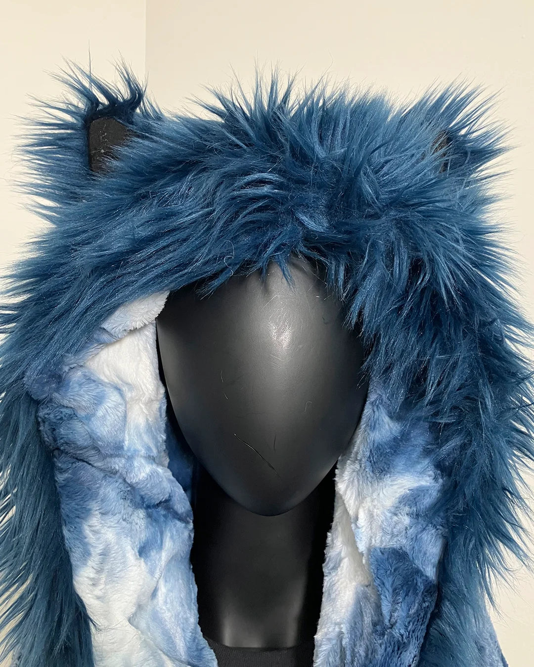 Blue furry hood on a mannequin head against a beige background