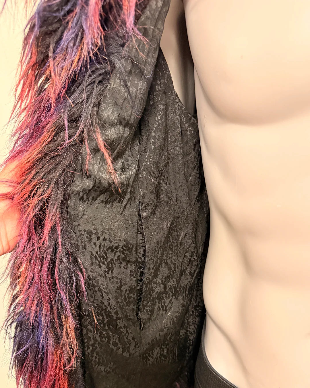 Close-up of a textured fabric with colorful fringe and a neutral background