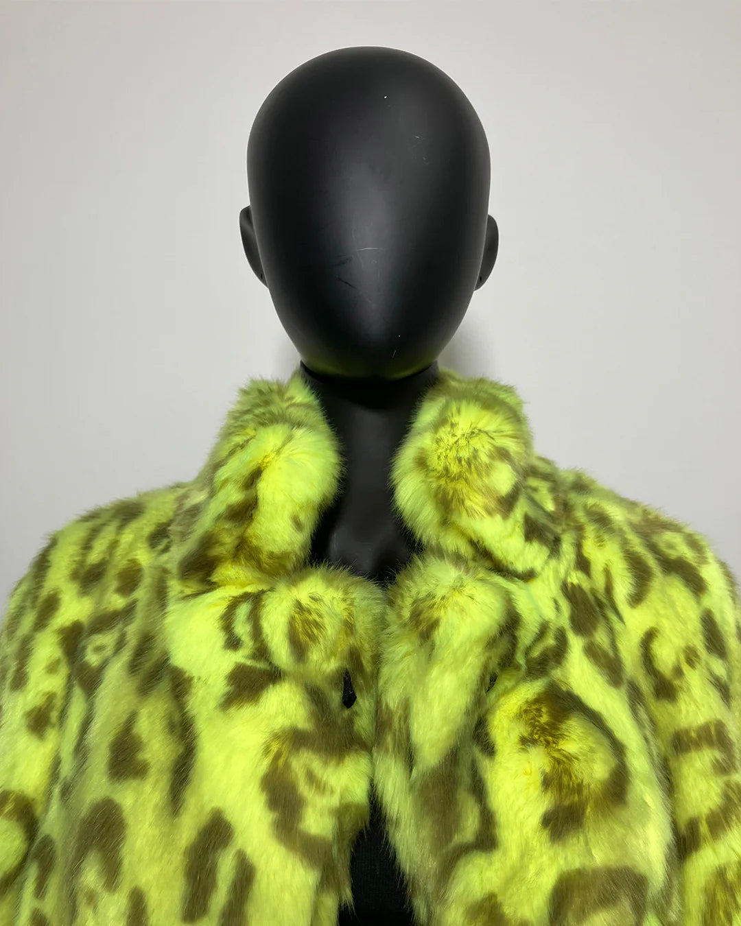 Mannequin wearing a bright yellow leopard print coat against a plain background
