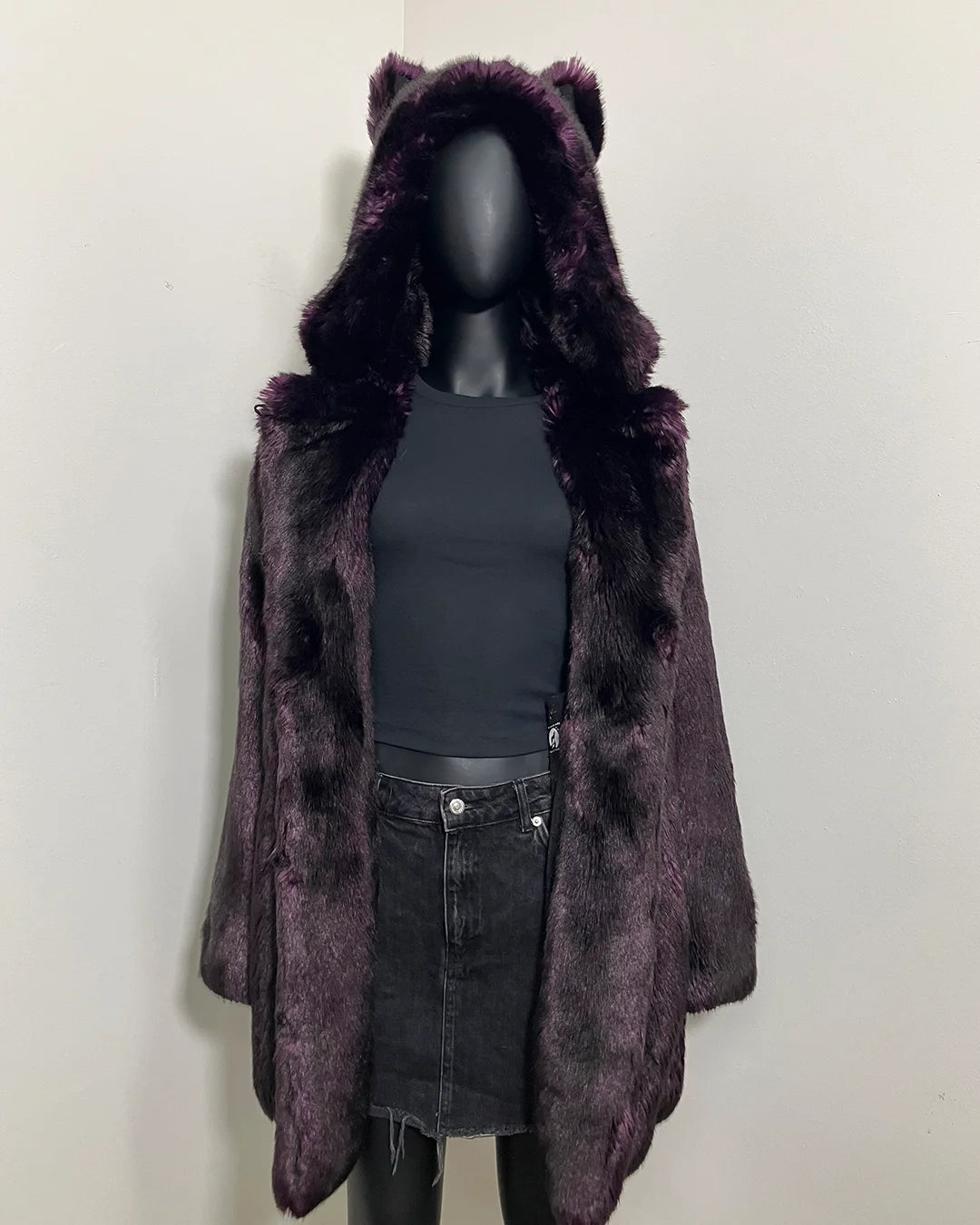 Mannequin wearing a dark purple faux fur coat with wolf ears on a white background