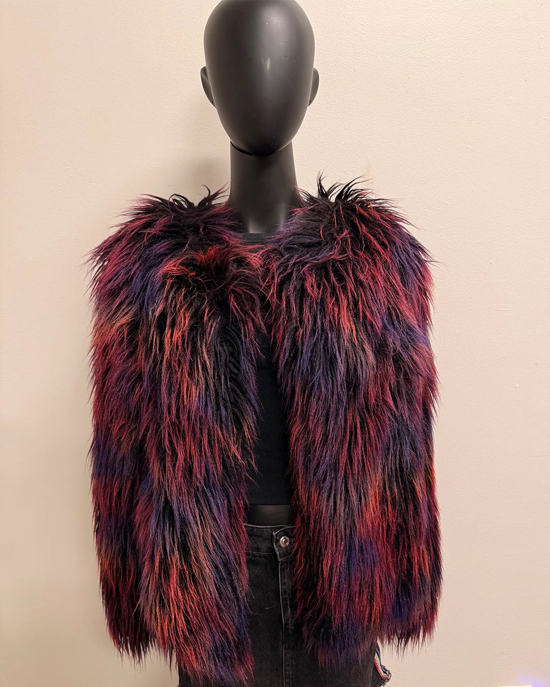Multicolored fake fur jacket on a mannequin against a beige background