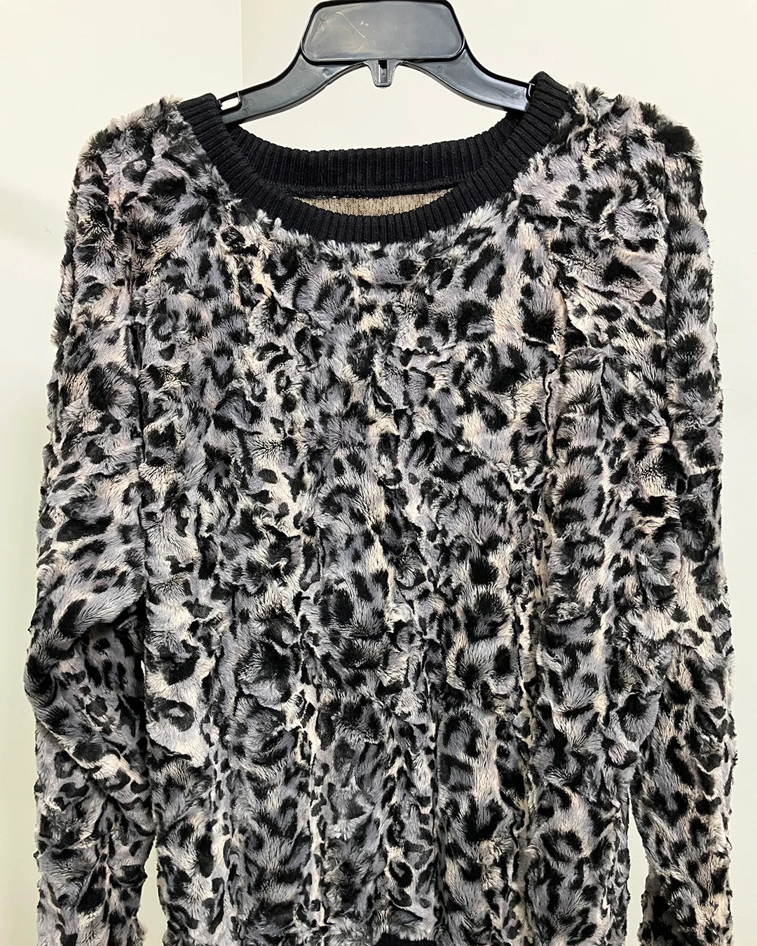 grey/black Leopard print sweater on a hanger against a white background