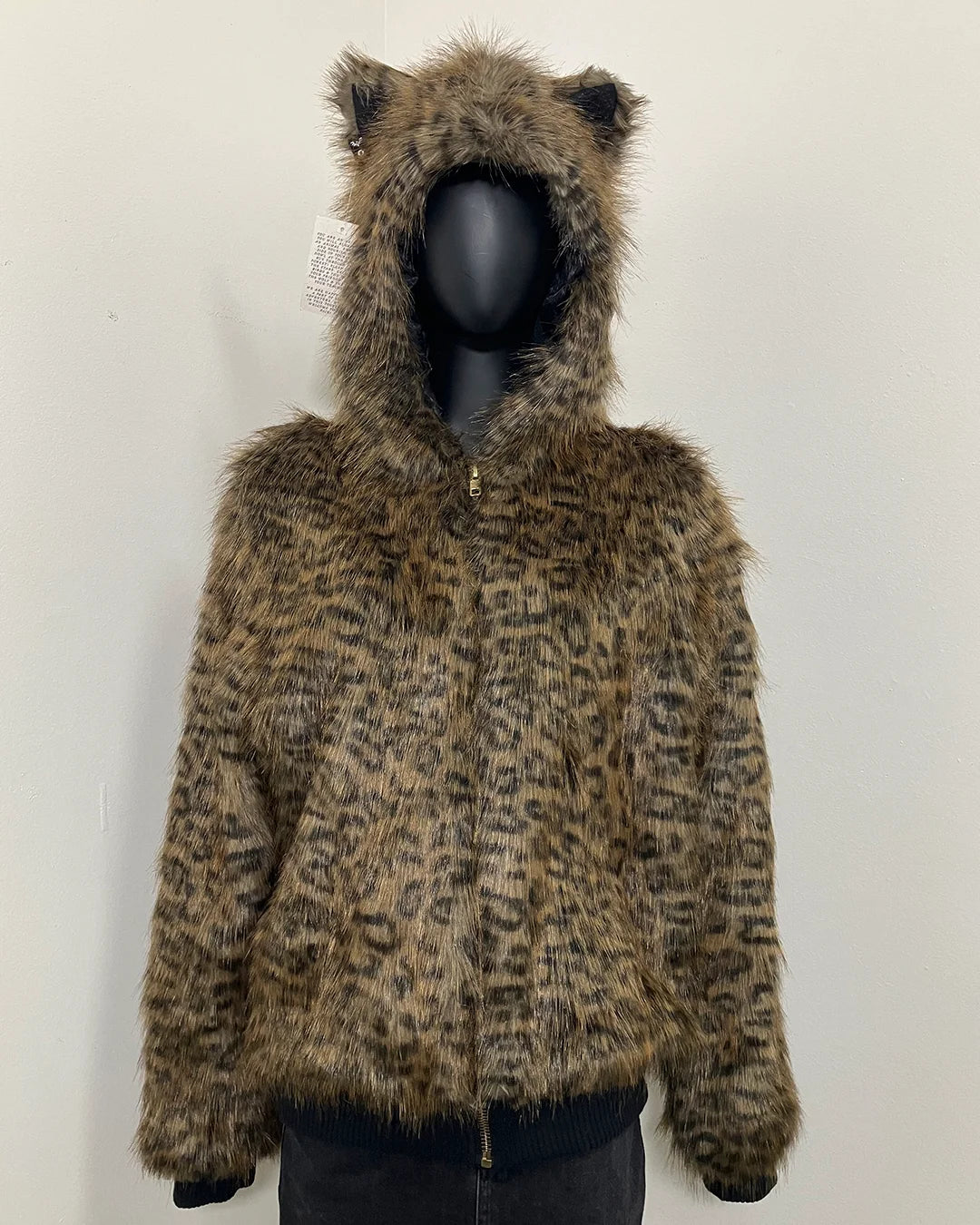 Leopard print bomber jacket with zipper closure, oversized hood and ears, with black ribbing at the bottom of the bomber jacket and at the ends of the arms, on a mannequin against a white background