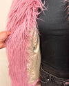 Close-up of a pink fluffy garment held by a person wearing a black top and jeans.