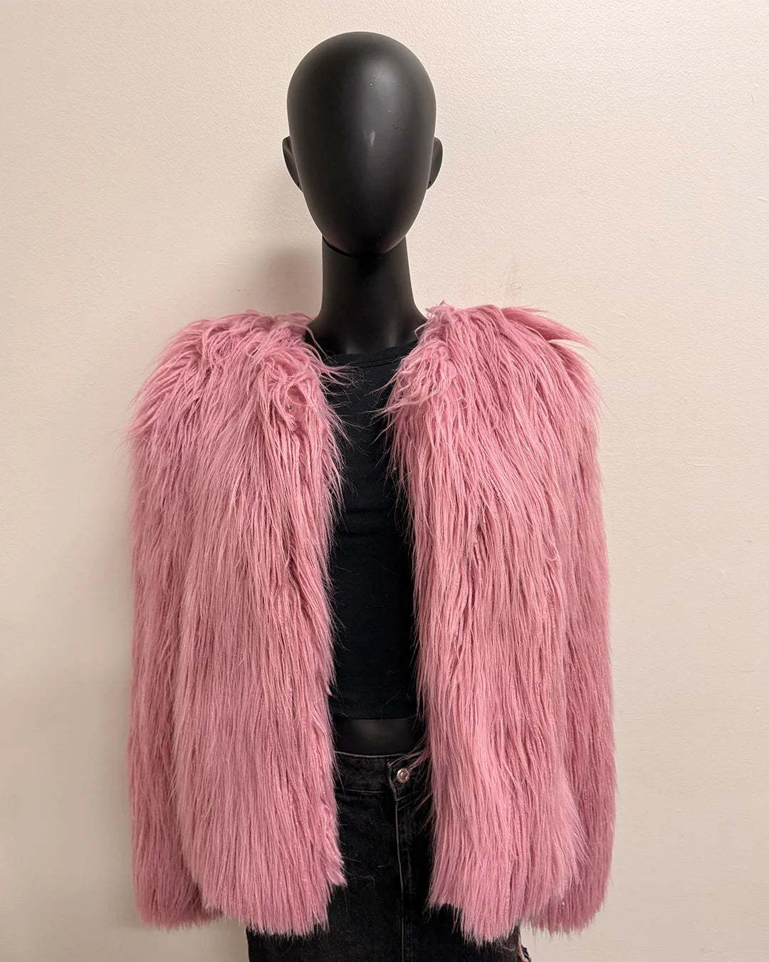 Pink fluffy jacket on a mannequin against a beige background