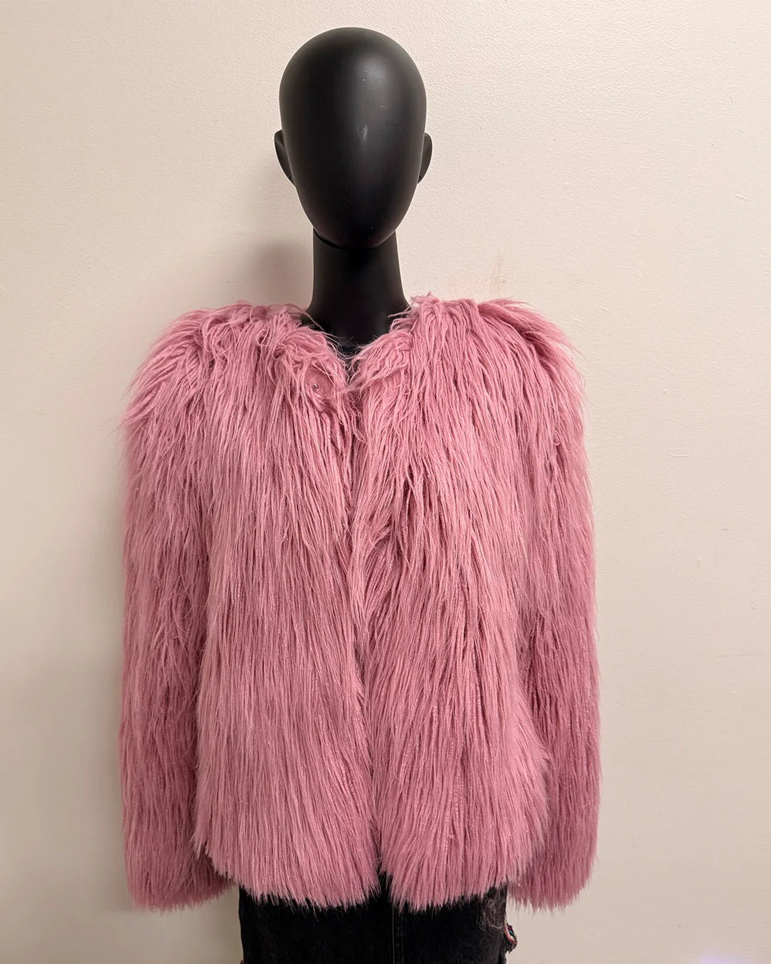 Pink fluffy jacket on a mannequin against a plain background
