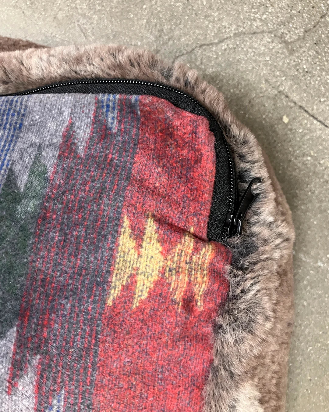 Multicolored patterned petbed with fur trim on a concrete surface
