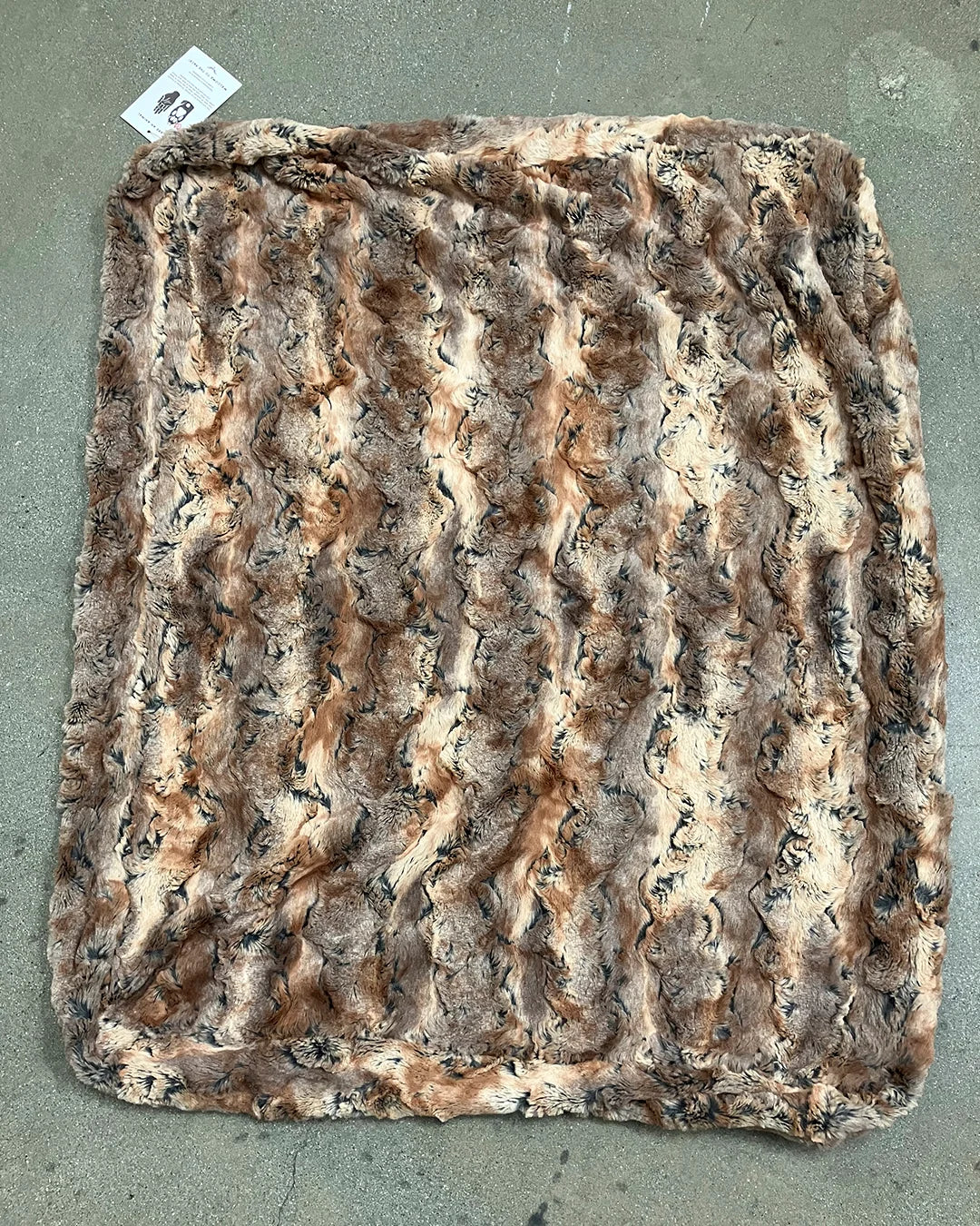 Brown textured faux fur pet bed on a concrete surface