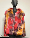 A multicolor faux fur coat with red, orange, yellow, and purple tones, displayed on a black mannequin in front of  a plain off-white wall.