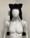 Black furry hat with cat ears and pom-poms on a mannequin 