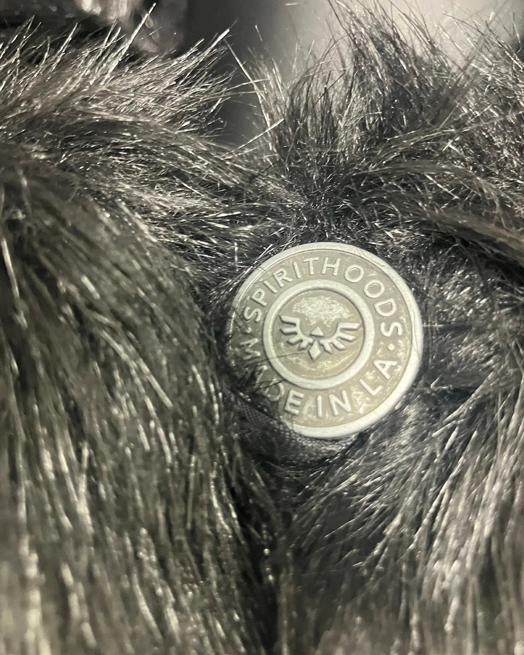 close-up photo of SpiritHoods custom button and "Made in Los Angeles" verbiage on button. SpiritHoods Online Sample Sale Style: Hooded Faux Fur Coat - Black Panther in Size X-SMALL