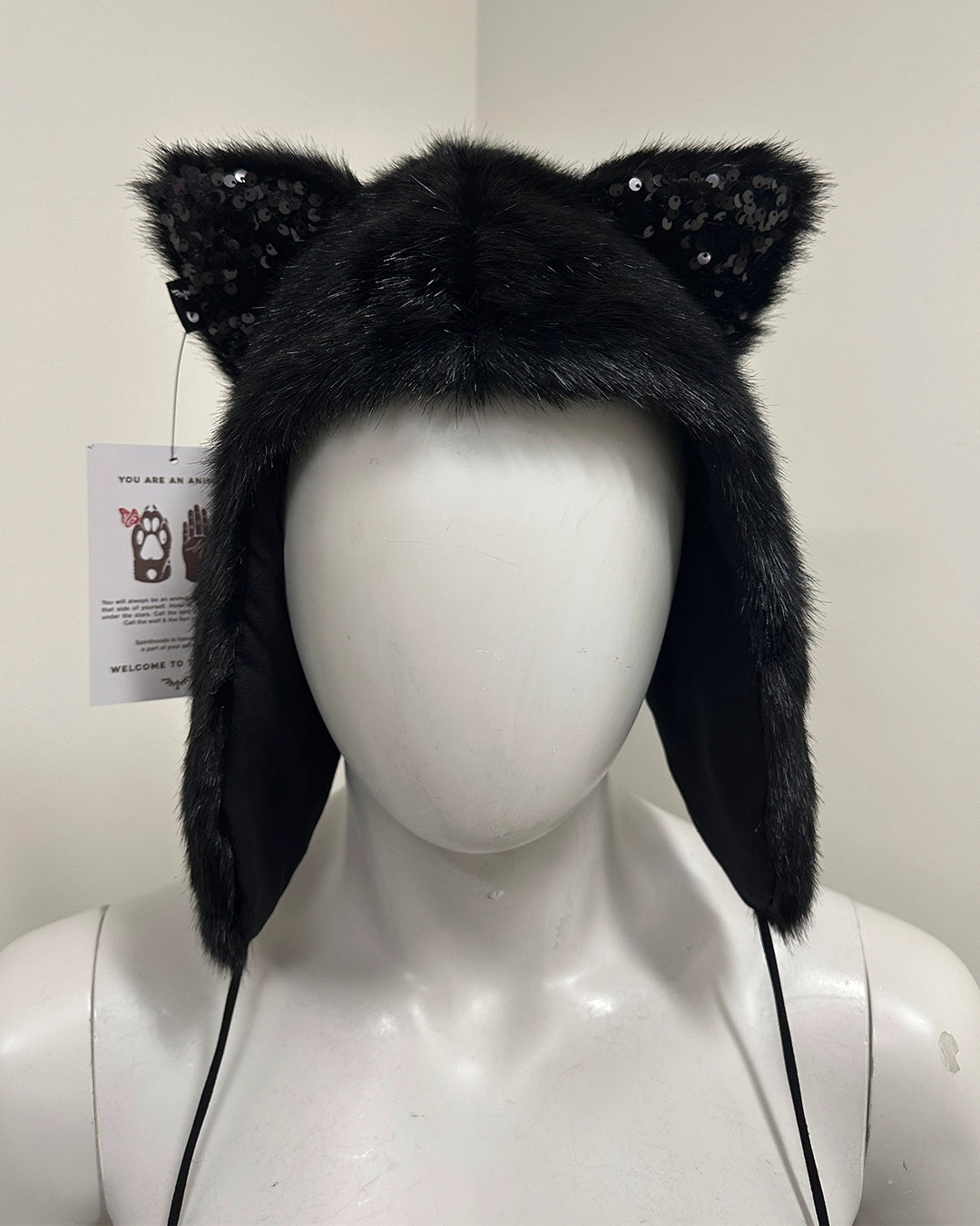Black furry hat with cat ears and pom-poms on a mannequin 