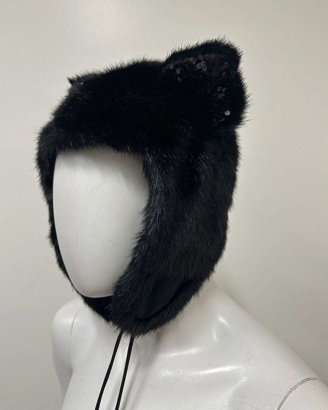 Black fur hat with decorative bow on a mannequin head 