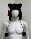 Black furry hat with ear flaps and pom-poms on a mannequin 