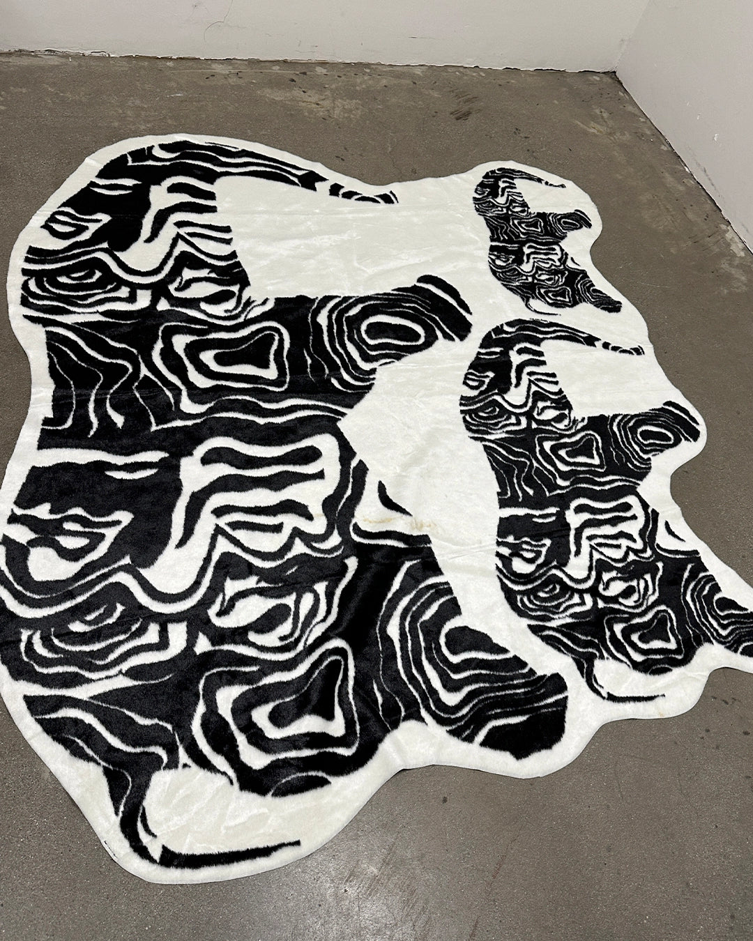 Black and white abstract pattern fur rug on a concrete floor