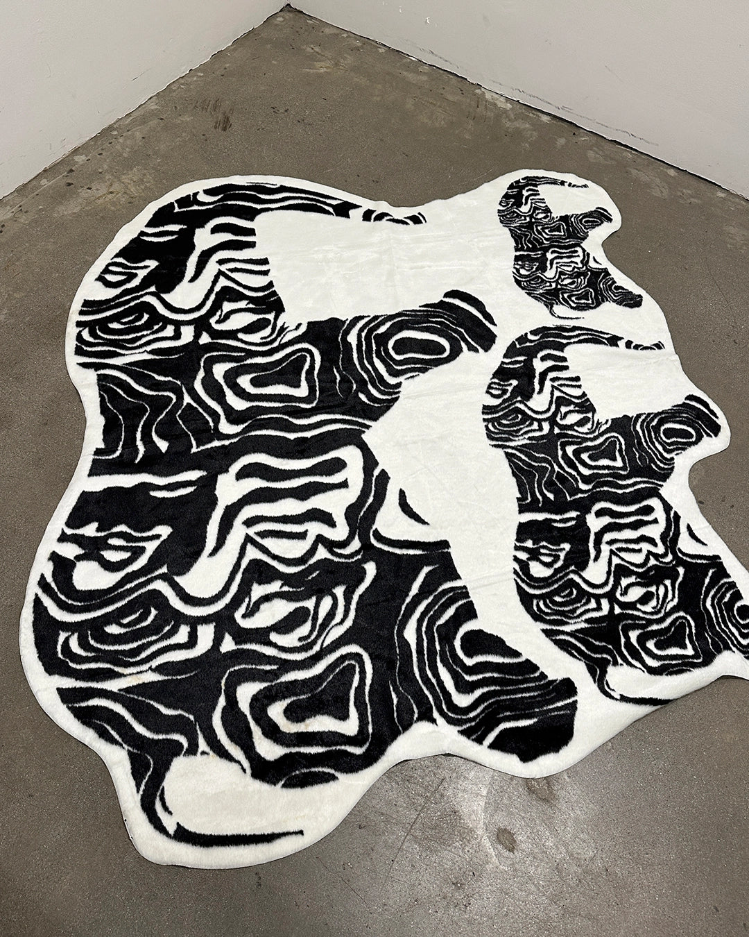 Black and white patterned fur rug shaped like a cat  