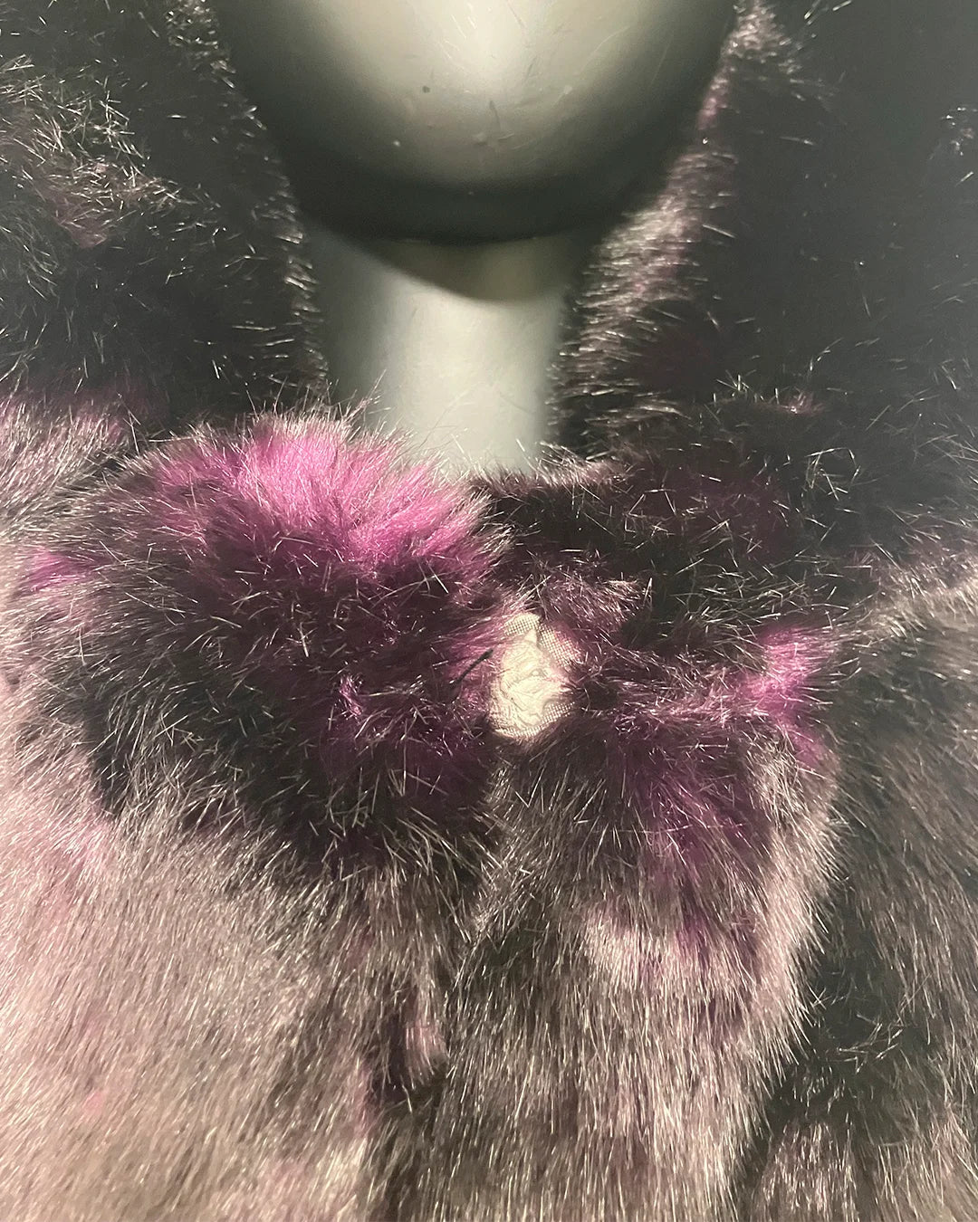 Close-up of a fluffy purple faux fur coat where the plush faux fur meets the wolf face button closure.