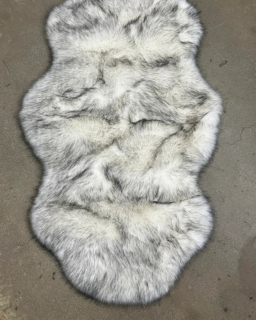 white faux fur with black tips, creating a husky inspired faux fur fur rug on a concrete floor
