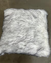 Furry white faux fur pillow on a brown surface