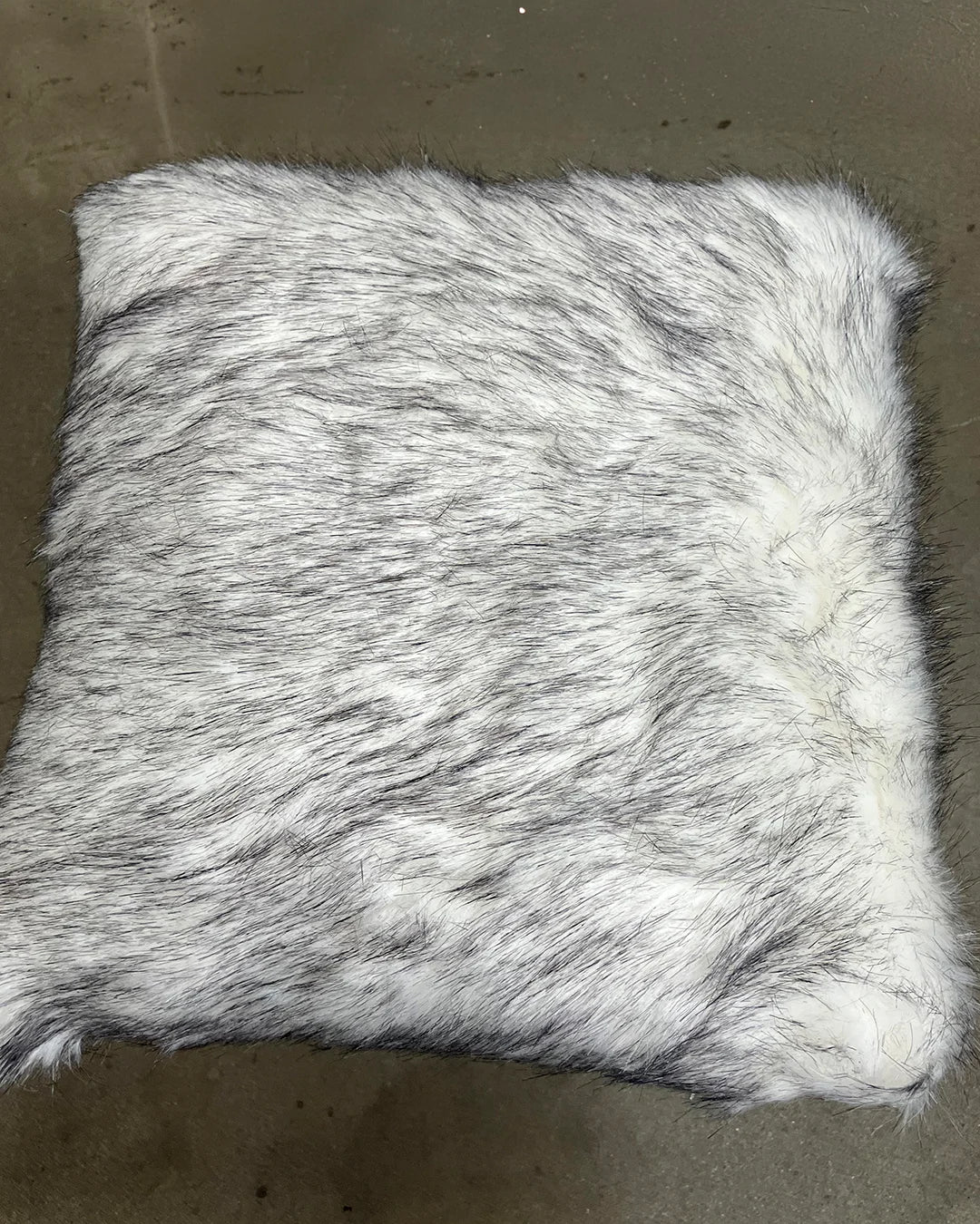 Furry white faux fur pillow on a brown surface