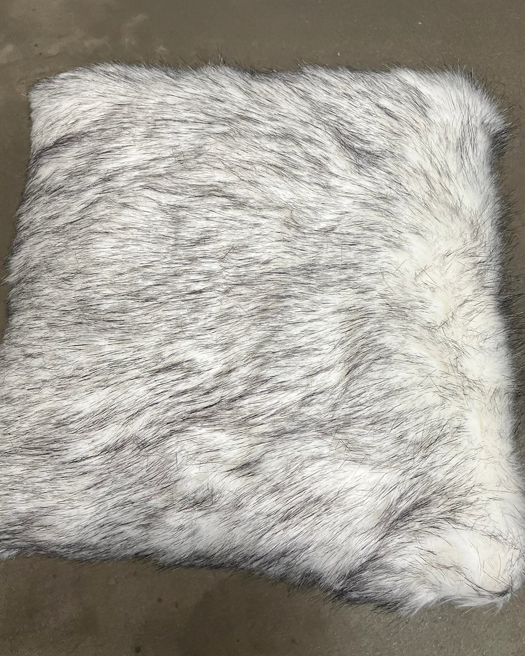 husky inspired white and black faux fur pillow on a brown background