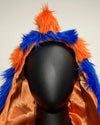 Mannequin head wearing a colorful hood with orange and blue fake fur on a plain background