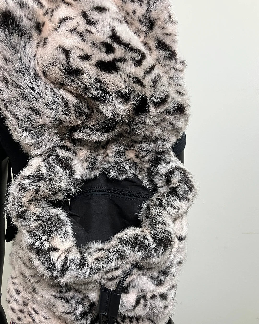 Close-up of a fake fur backpack and the inner pocket with a white tiger pattern on a plain background