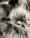Close-up of a fake fur backpack showing the broken metallic zipper.